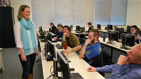 Associate Degree in Computer Science Students in a computer lab classroom paying attention to the instructor at the front of the classroom