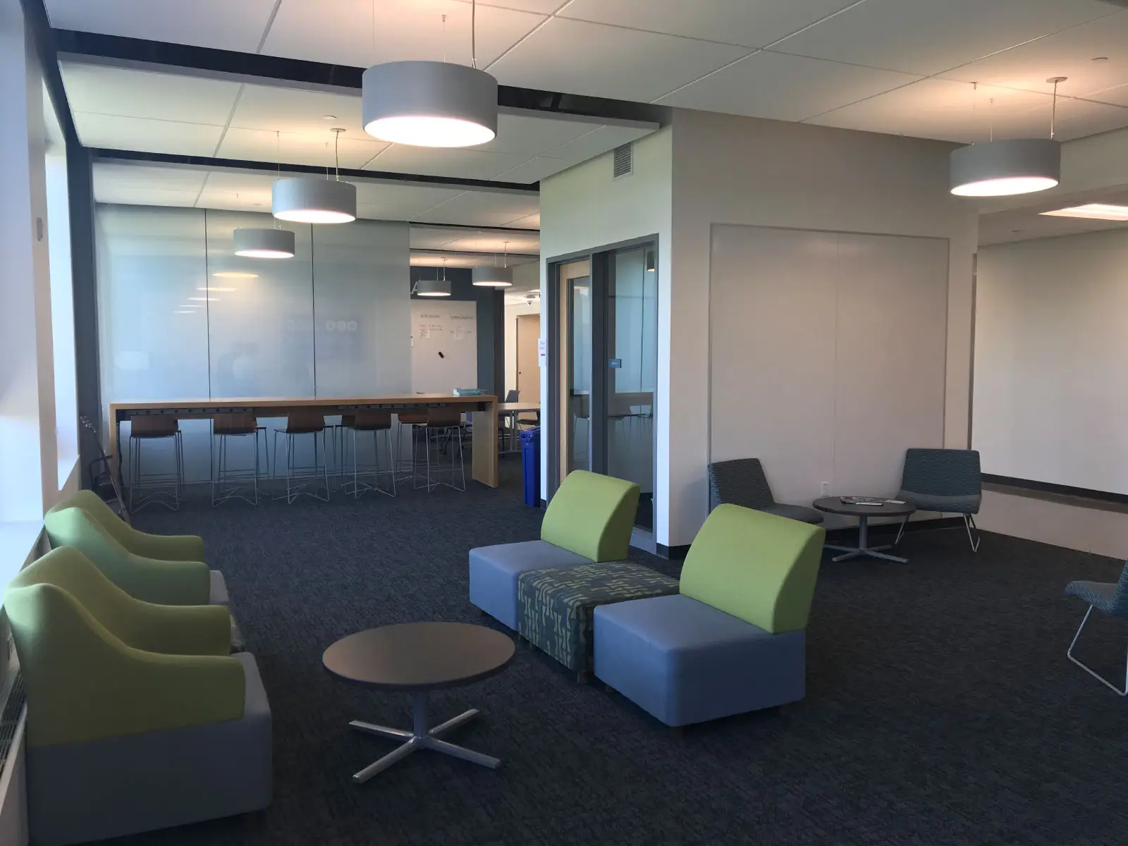 Various small meeting spaces with green and blue chairs in the Harmony campus lobby