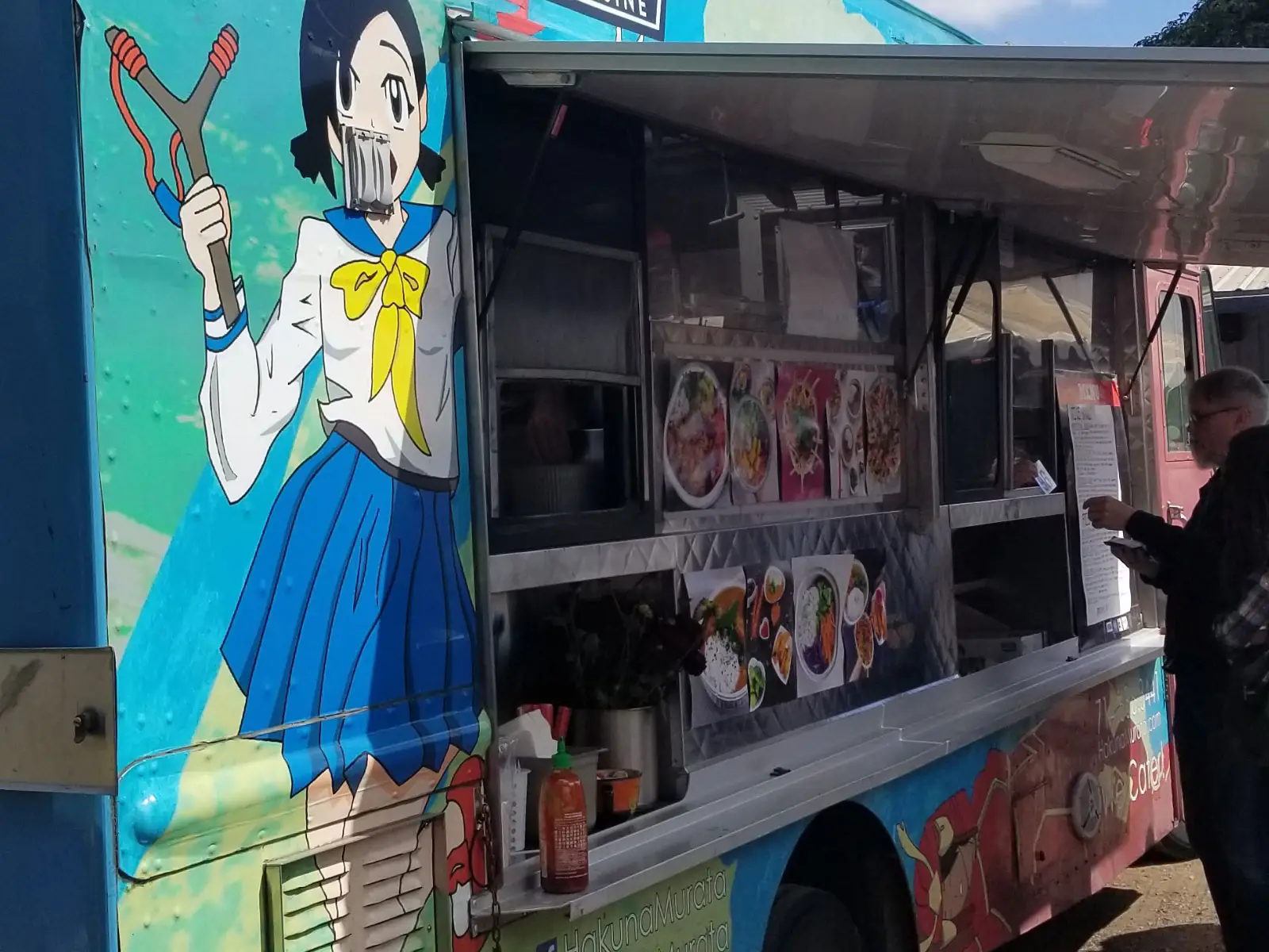 "Hakuna Murata", a Japanese and Filipino Cuisine food truck, featuring an anime character painted on its side, parked at the Wilsonville campus "Hakuna Murata", a Japanese and Filipino Cuisine food truck, featuring an anime character painted on its side, parked at the Wilsonville campus