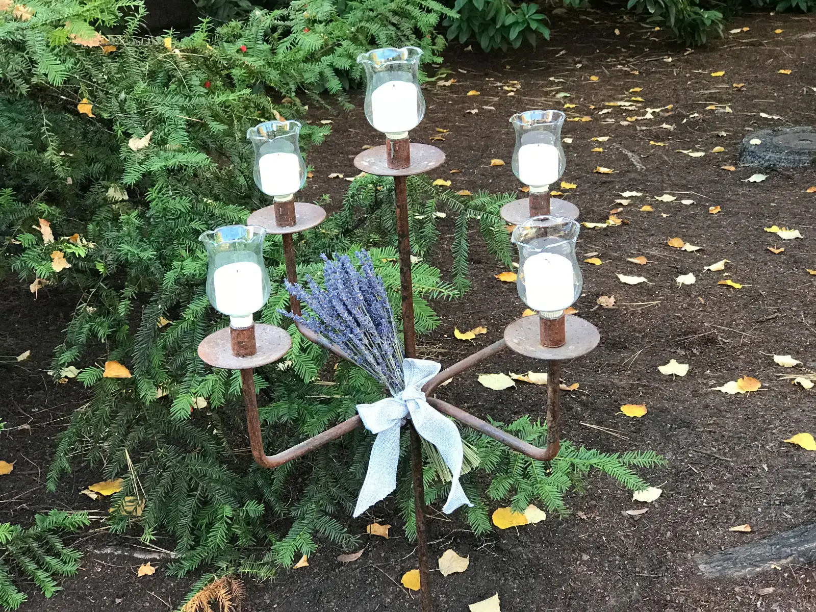 A five-candle metal centerpiece, set in the outside garden of the Oregon City campus A five-candle metal centerpiece, set in the outside garden of the Oregon City campus