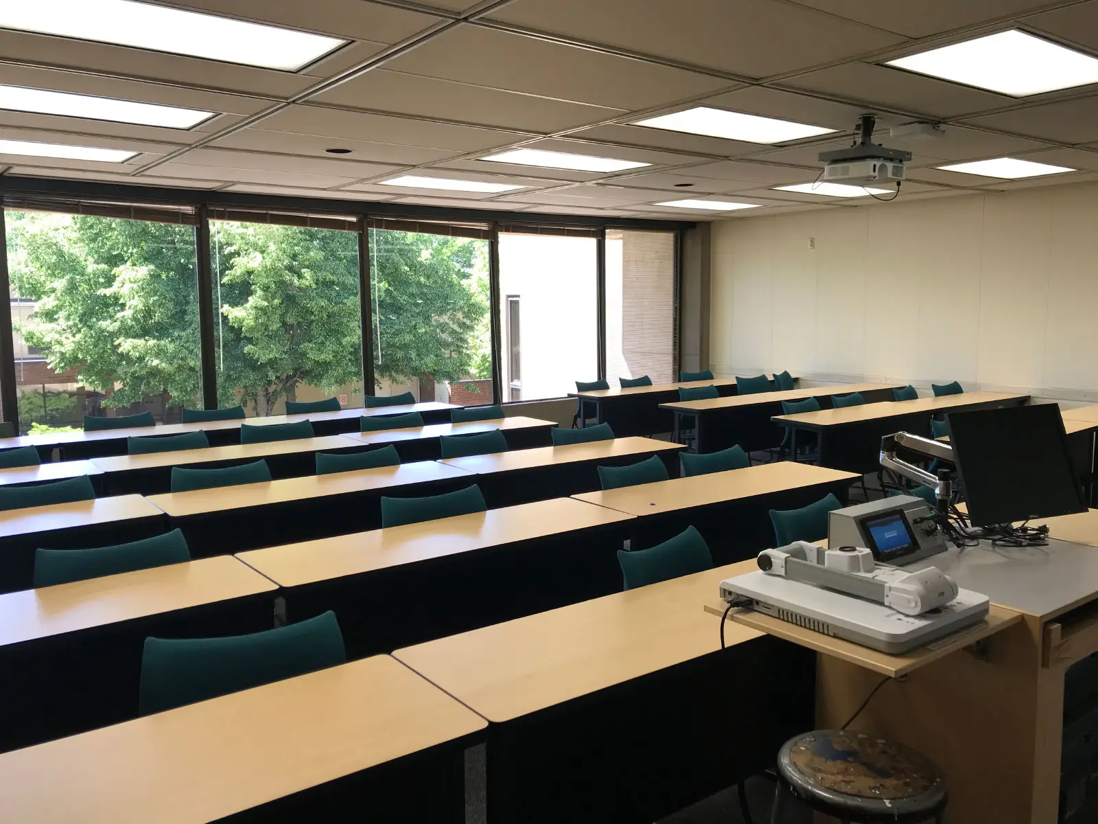 Rows of tables and blue chairs in front of a podium, next to ceiling-high windows in a classroom at the Oregon City campus Rows of tables and blue chairs in front of a podium, next to ceiling-high windows in a classroom at the Oregon City campus