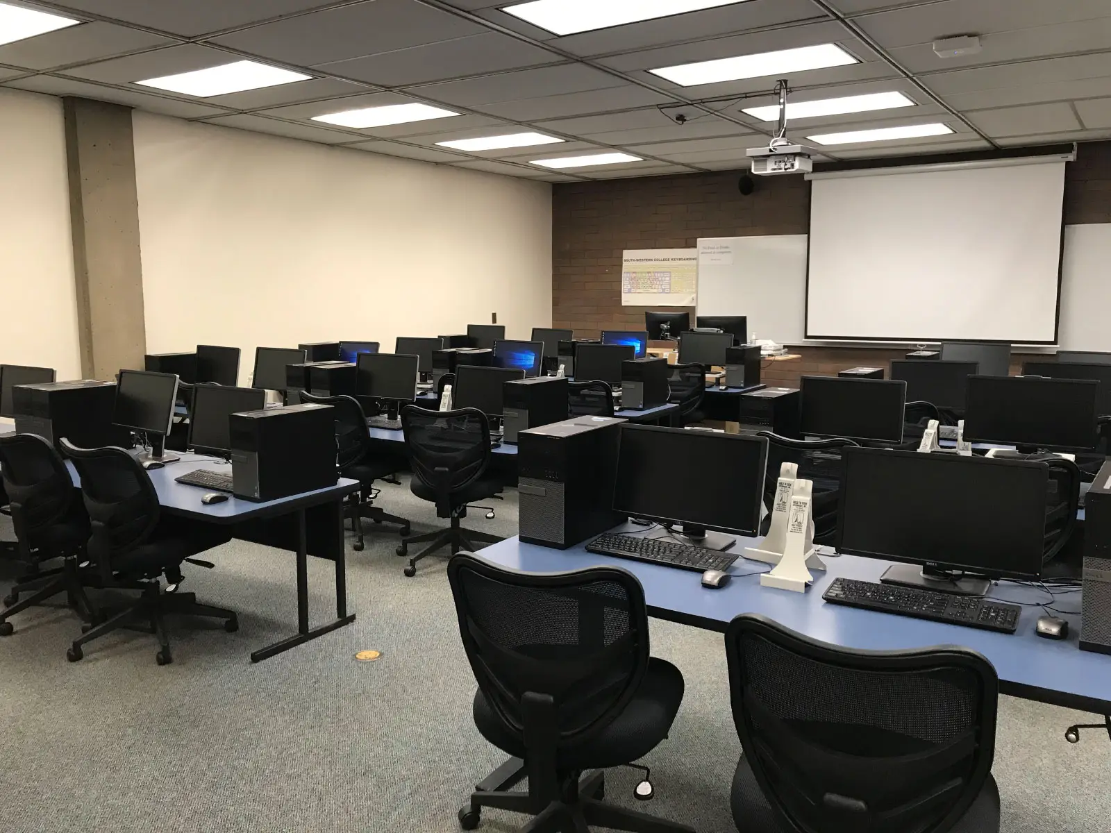 Rows of tables with computers and comfortable, ergonomic chairs in front of a projector screen in a computer lab on the Oregon City campus Rows of tables with computers and comfortable, ergonomic chairs in front of a projector screen in a computer lab on the Oregon City campus